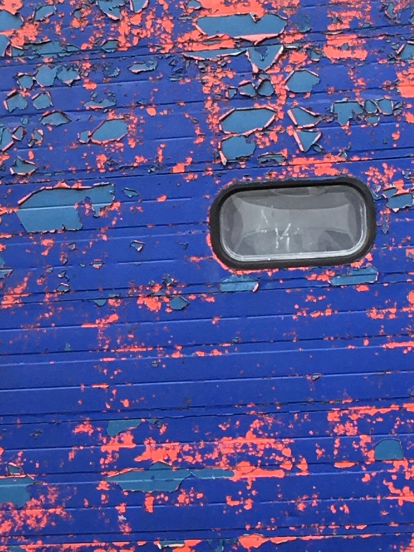 Photo of peeling blue and red paint on a panelled door