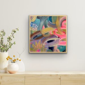 photo of a colourful abstract painting on a neutral wall above a cabinet